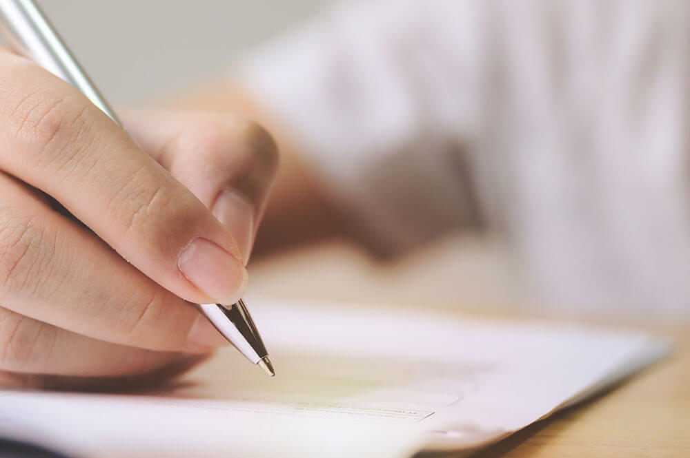 Closeup of Hand with Pen Over Paper