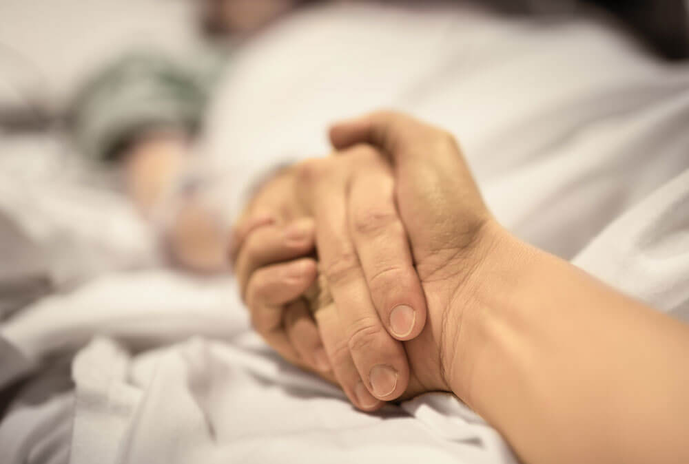 Closeup of Holding Hands in Hospital Bed